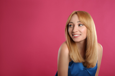 Photo of Beautiful young woman with blonde hair on pink background. Space for text