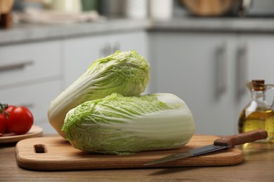 Fresh Chinese cabbages, knife, tomatoes and oil on wooden table in kitchen