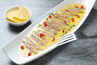 Photo of Tasty pickled anchovies with spices on gray table, closeup