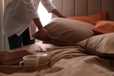 Woman making bed with stylish linens in room, closeup