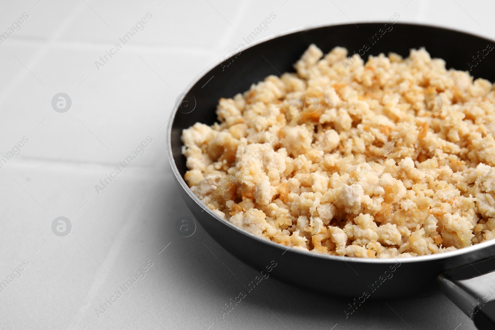 Photo of Fried ground meat in frying pan on white tiled table, closeup. Space for text