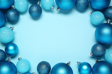 Frame of beautiful Christmas balls on light blue background, top view. Space for text
