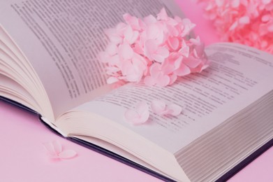 Beautiful hortensia flowers and book on pink background, closeup