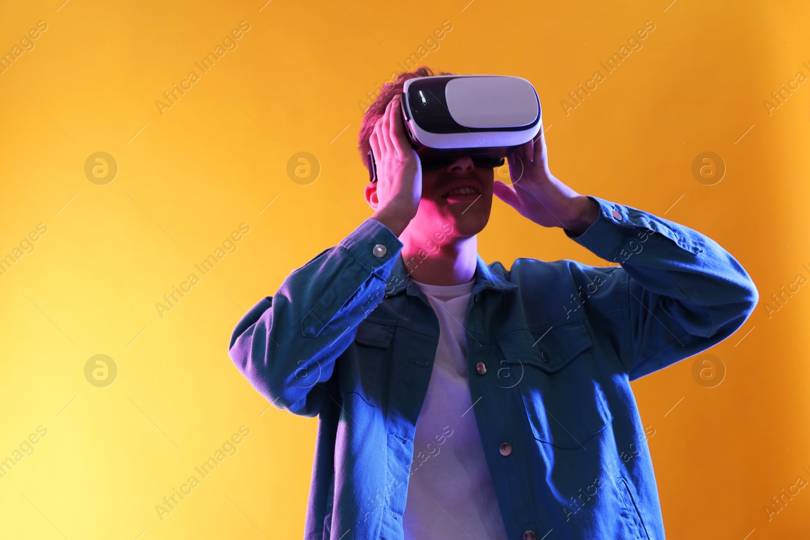 Photo of Young man with virtual reality headset on yellow background. Space for text