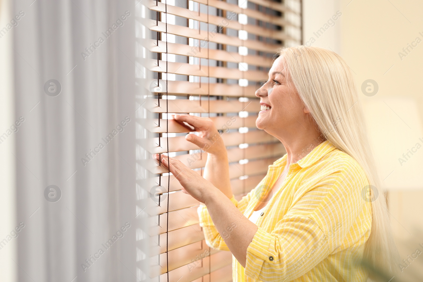 Photo of Portrait of happy mature woman near window indoors