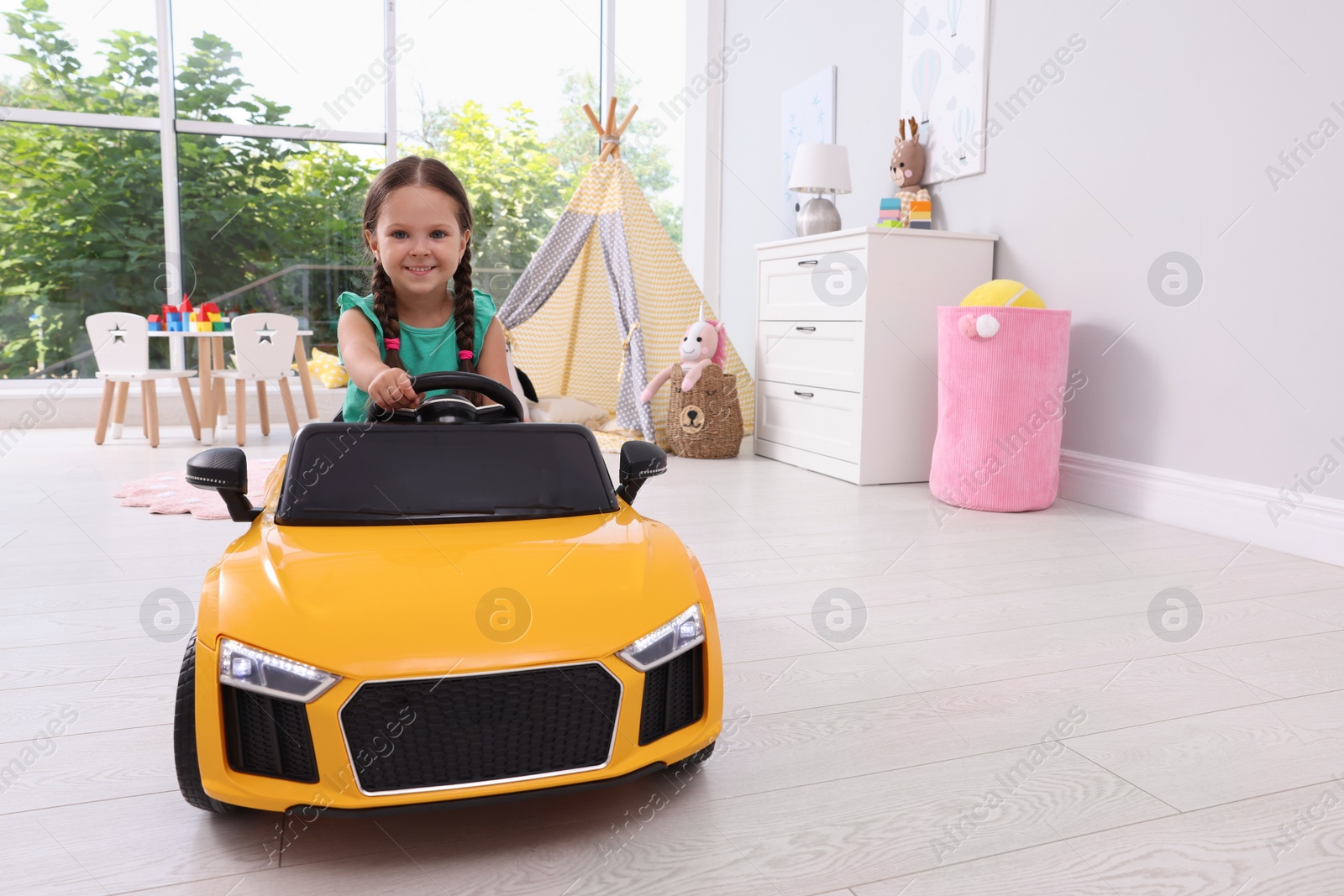 Photo of Adorable child driving toy car in room at home