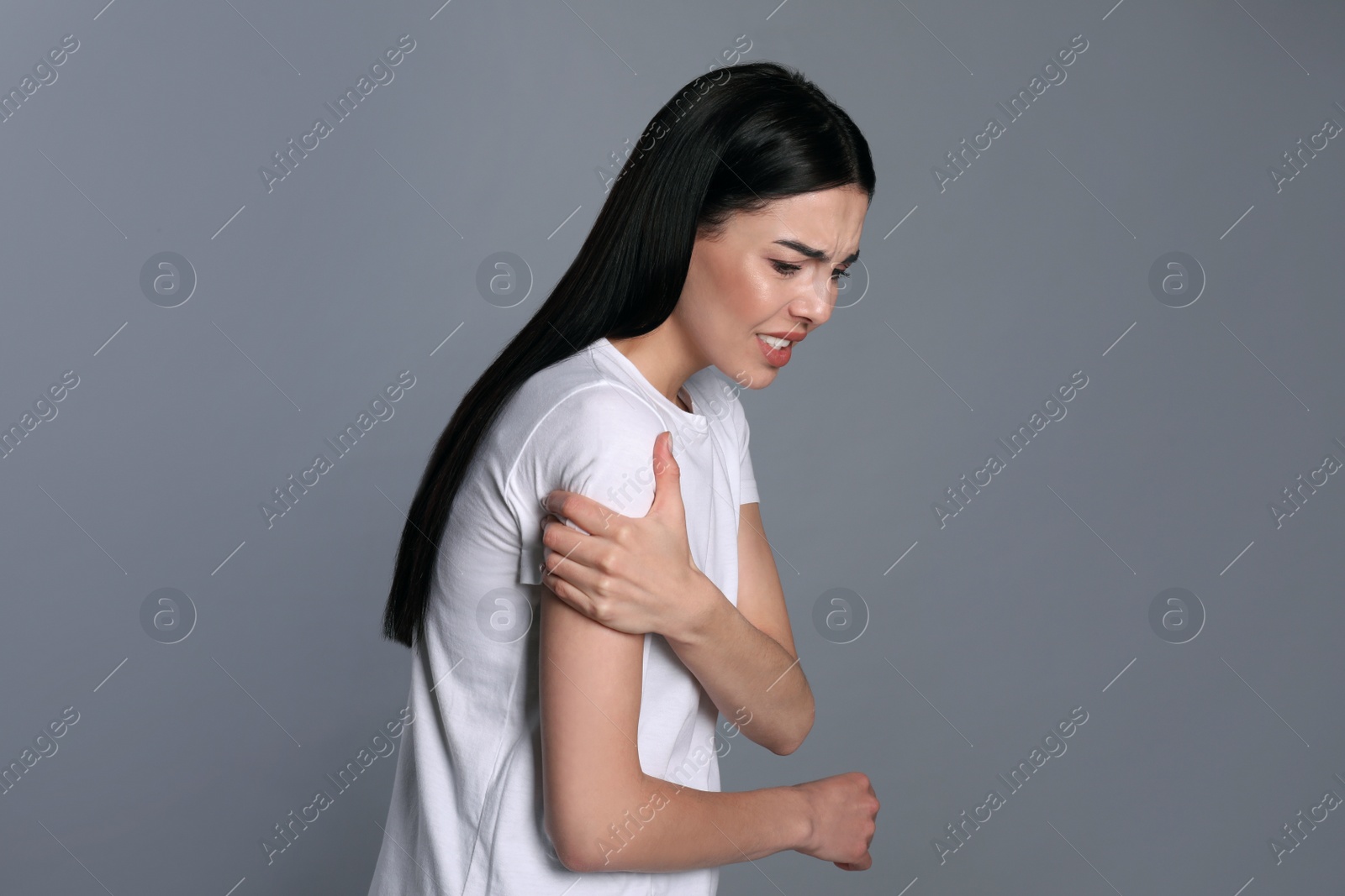 Photo of Woman suffering from shoulder pain on grey background