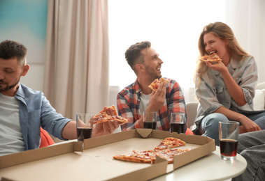 Group of friends eating tasty pizza at home