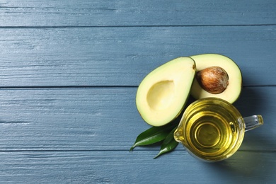 Photo of Gravy boat with oil and ripe fresh avocado on wooden table, top view