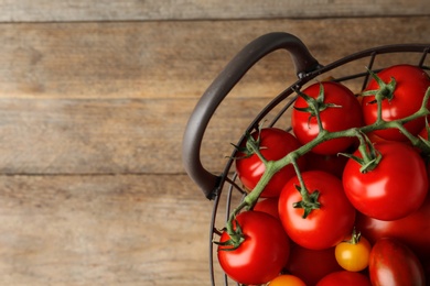 Photo of Fresh ripe tomatoes in basket on wooden table, top view. Space for text