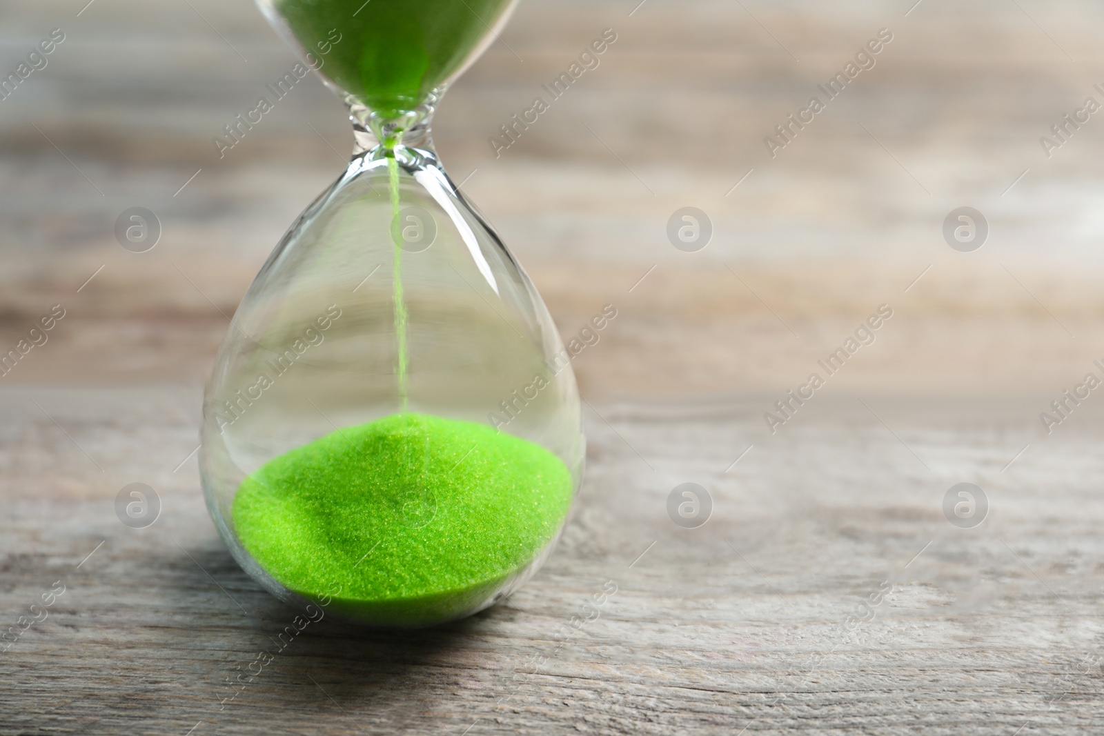 Photo of Hourglass with flowing sand on table. Time management
