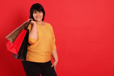 Photo of Beautiful overweight mature woman with shopping bags on red background. Space for text