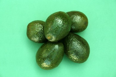 Photo of Many tasty ripe avocados on turquoise background, top view