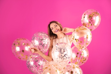 Young woman with air balloons on color background