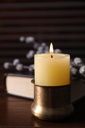 Photo of Burning candle on wooden table, closeup view