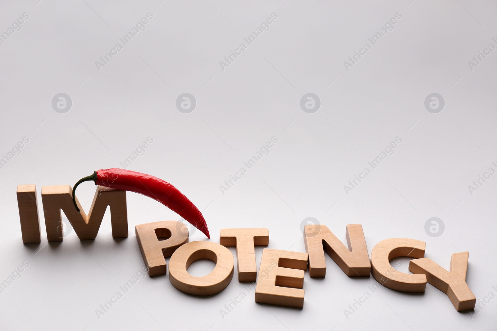 Photo of Chili pepper and word Impotency on light grey background. Space for text