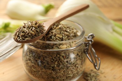 Photo of Jar and spoon with fennel seeds on table, closeup