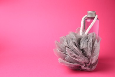 Photo of Grey shower puff and bottle of cosmetic product on pink background, space for text