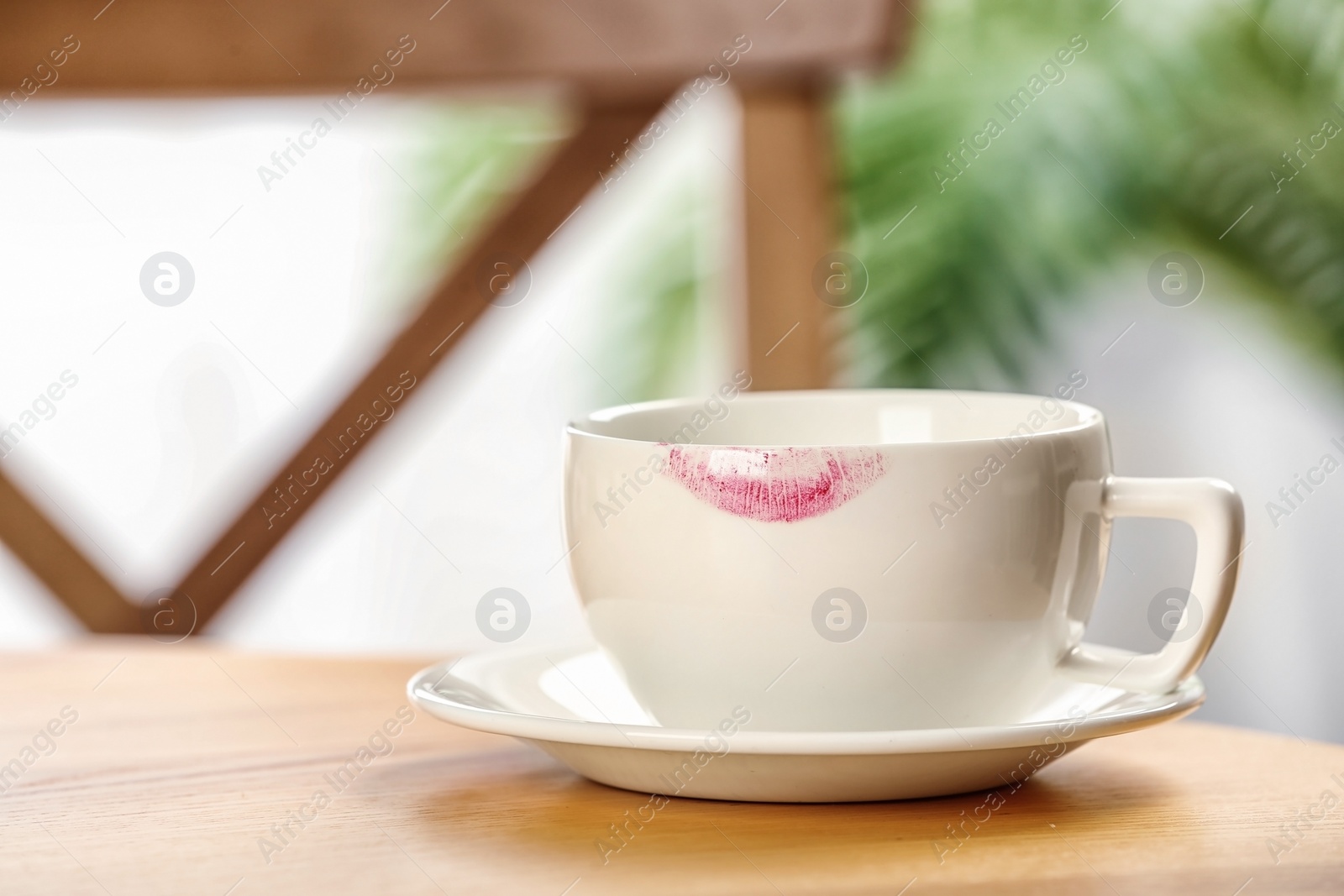 Photo of Ceramic cup with lipstick mark on table indoors. Space for text