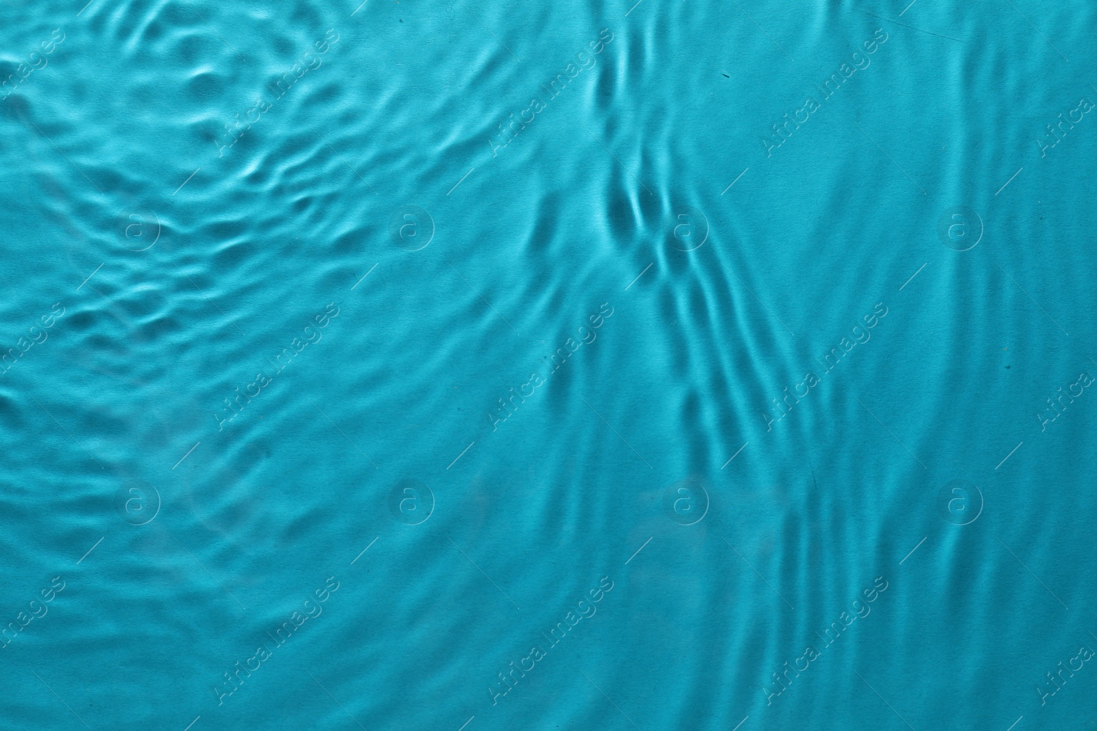 Photo of Rippled surface of clear water on light blue background, top view