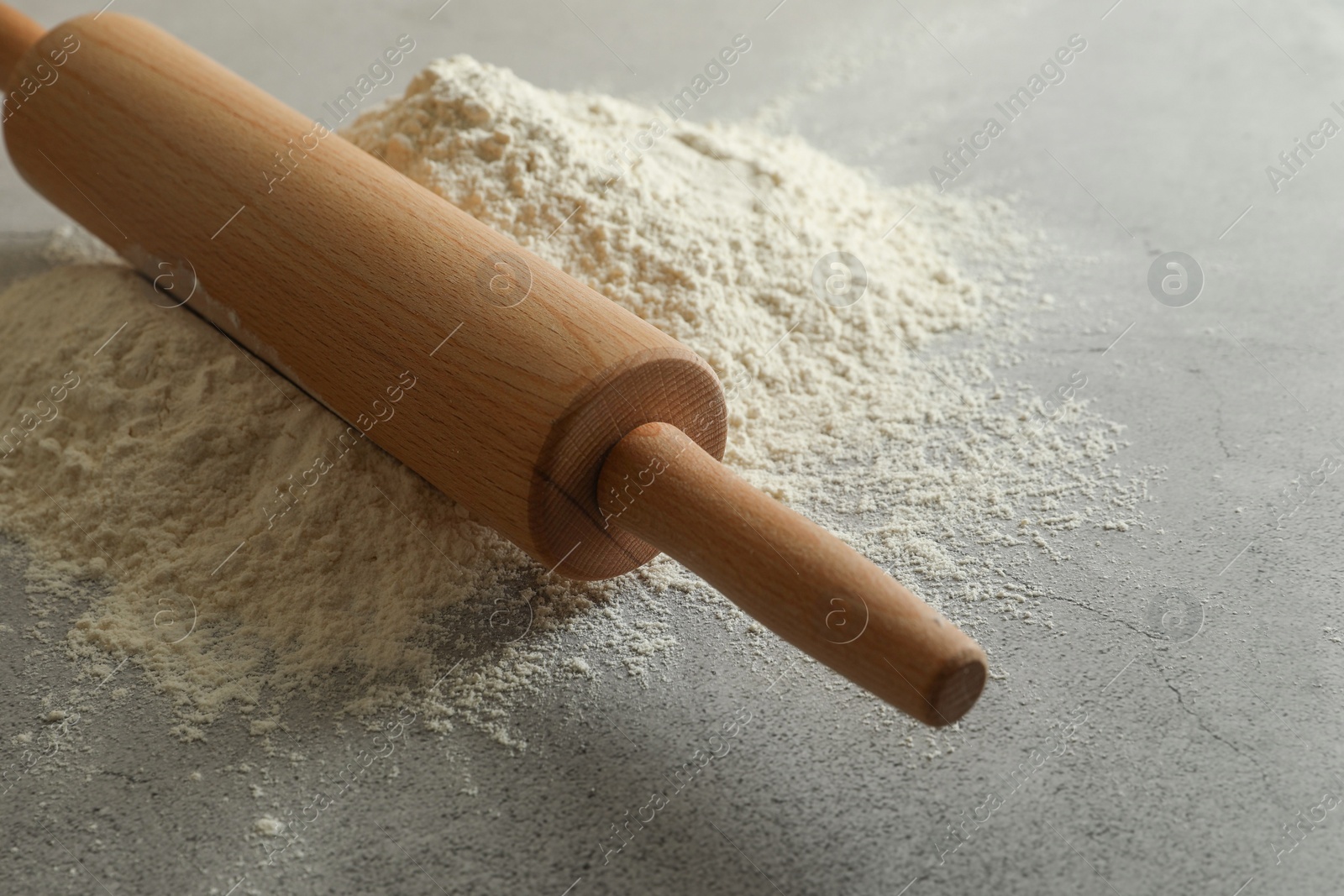 Photo of Flour and rolling pin on grey table, closeup