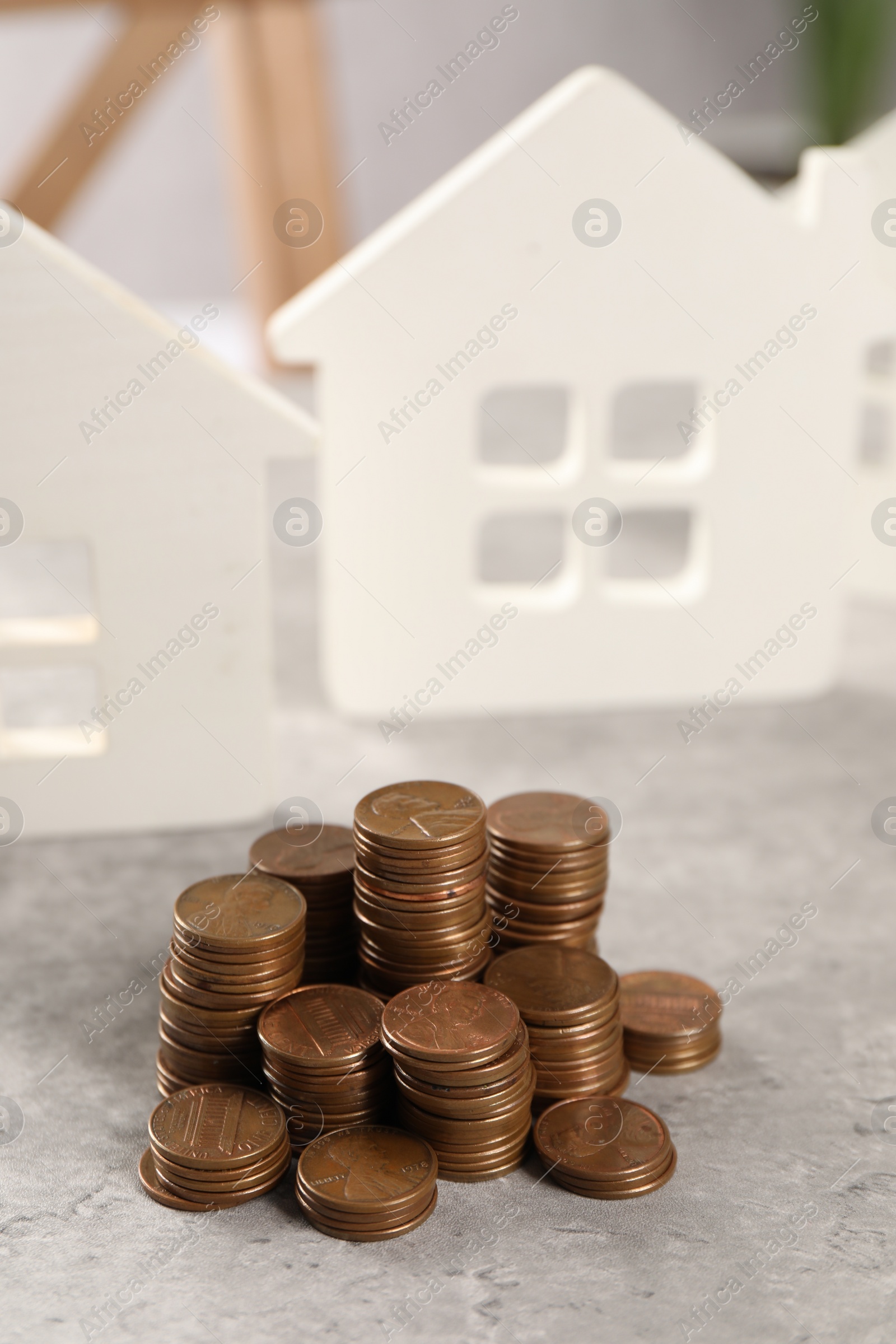 Photo of House models and stacked coins on grey table, selective focus