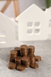 Photo of House models and stacked coins on grey table, selective focus