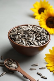 Photo of Raw sunflower seeds and flowers on grey table