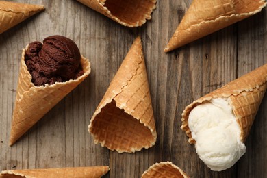 Ice cream scoops in wafer cones on wooden table, flat lay