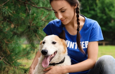 Photo of Female volunteer with homeless dog at animal shelter outdoors