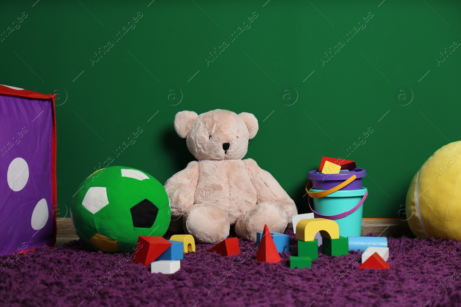 Photo of Set of different child toys on floor against color wall