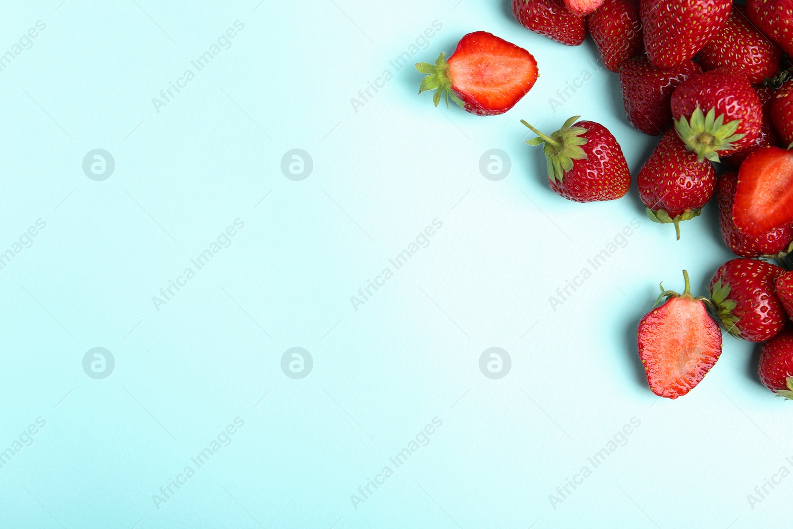 Photo of Tasty ripe strawberries on light blue background, flat lay. Space for text