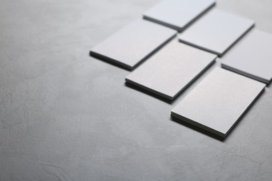 Blank business cards on light grey textured table, closeup. Mockup for design