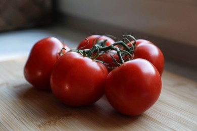 Photo of Branch of fresh tomatoes on wooden table, closeup