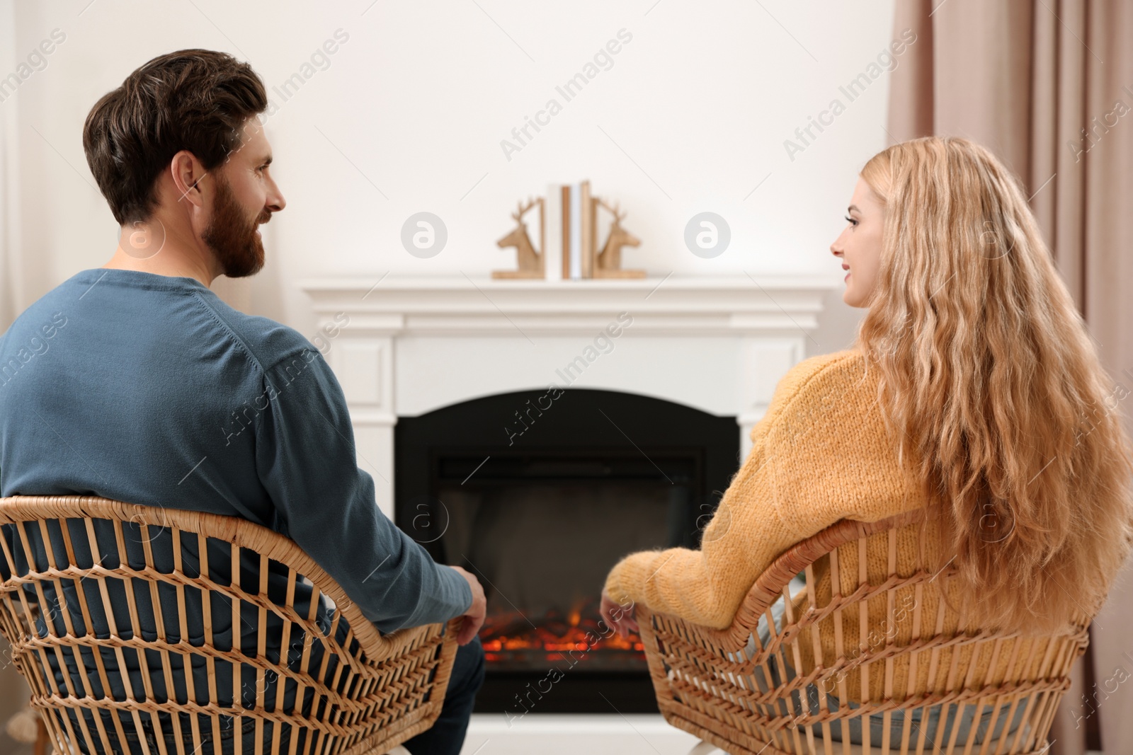 Photo of Lovely couple spending time together near fireplace indoors, back view
