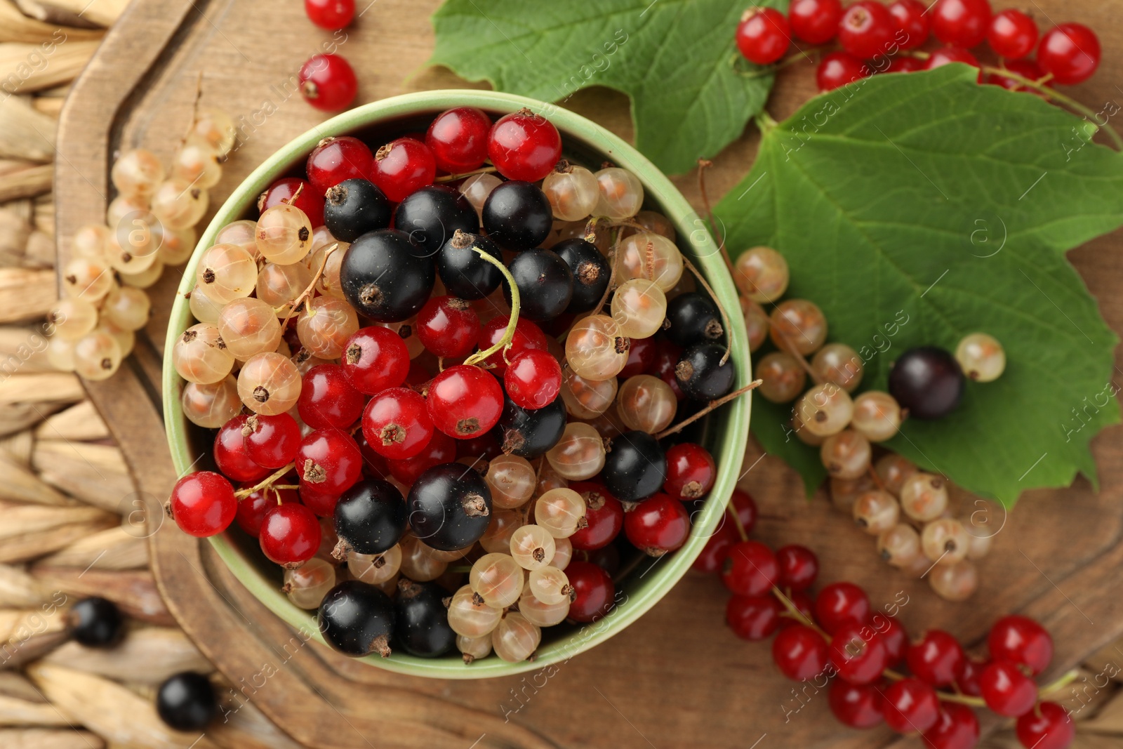 Photo of Different fresh ripe currants and green leaves on table, top view