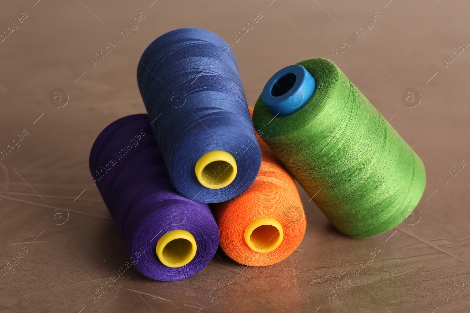 Photo of Set of color sewing threads on grey table, closeup