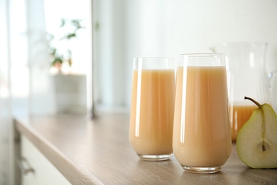 Tasty pear juice and cut fruit on wooden table, closeup