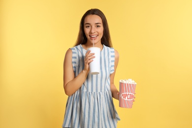 Woman with popcorn and beverage during cinema show on color background