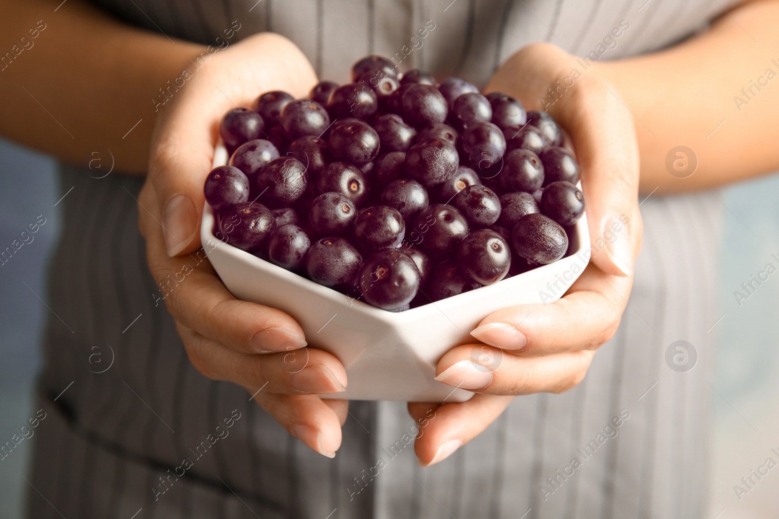 Photo of Woman holding bowl with fresh acai berries, closeup