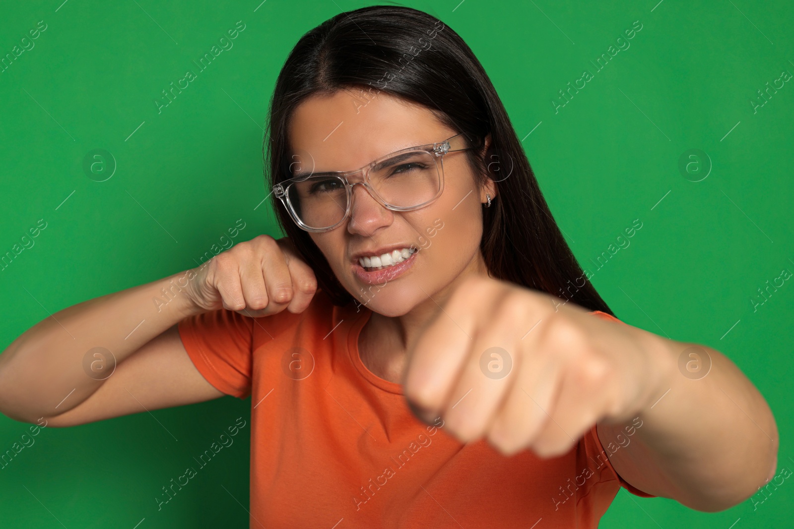 Photo of Young woman ready to fight on green background