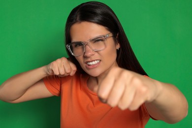 Photo of Young woman ready to fight on green background