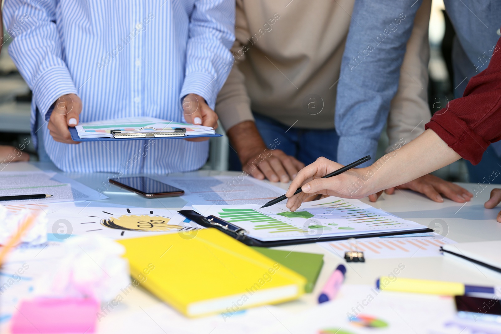 Photo of Team of employees working with charts at table, closeup. Startup project