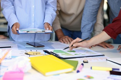 Photo of Team of employees working with charts at table, closeup. Startup project