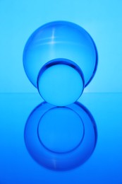Photo of Transparent glass balls on mirror surface against blue background