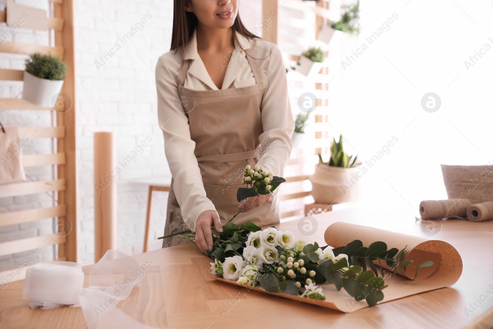 Photo of Florist making beautiful bouquet at table in workshop, closeup