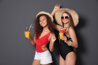 Beautiful young women in beachwear with cocktails on dark background