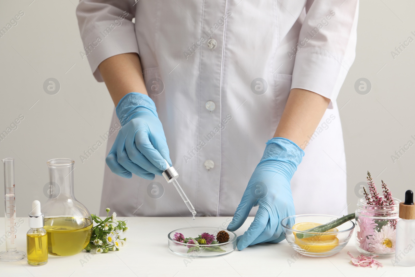 Photo of Scientist developing cosmetic oil at white table, closeup