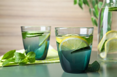 Photo of Refreshing water with cucumber, lemon and mint on green table. Space for text