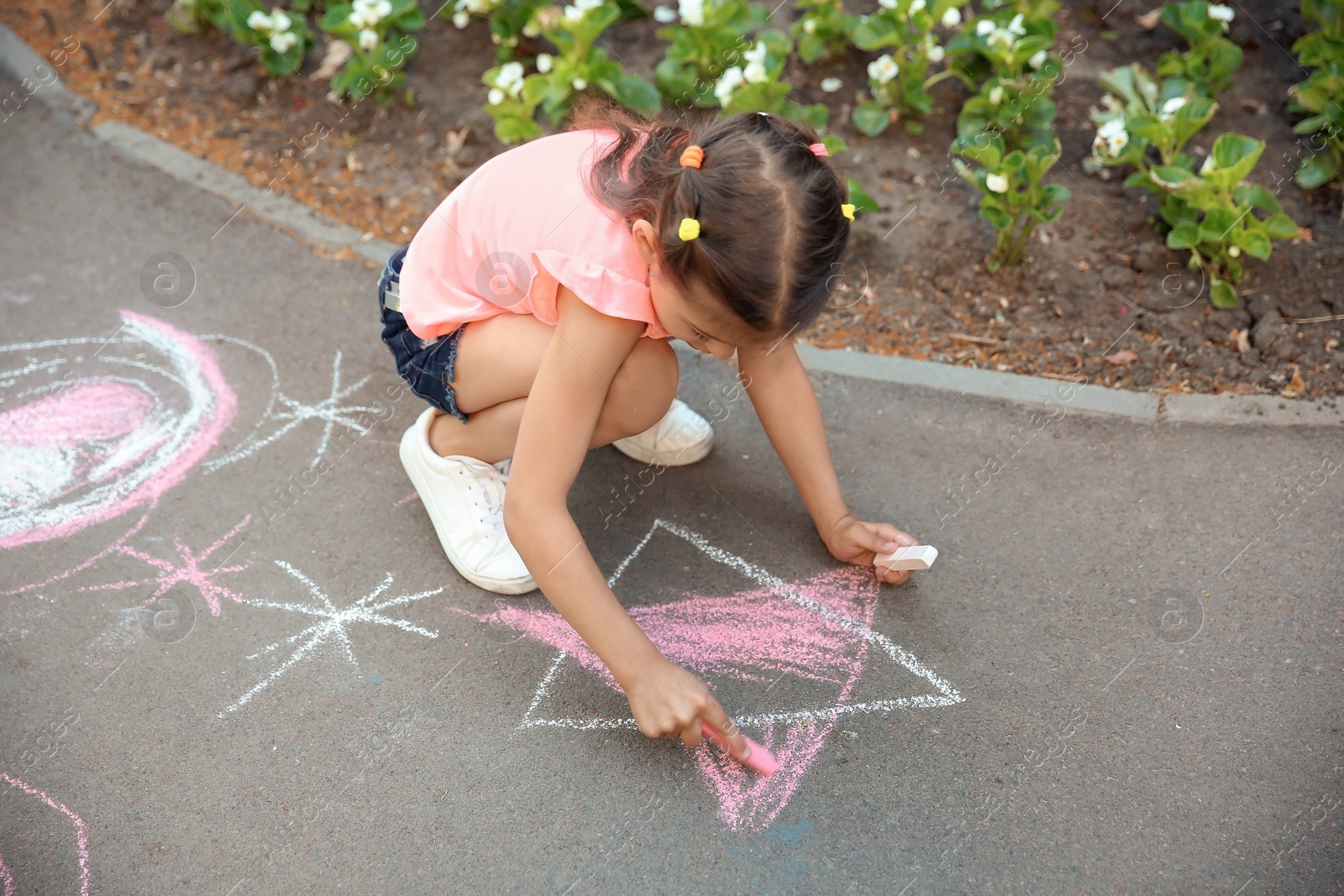 Photo of Little child drawing star with chalk on asphalt